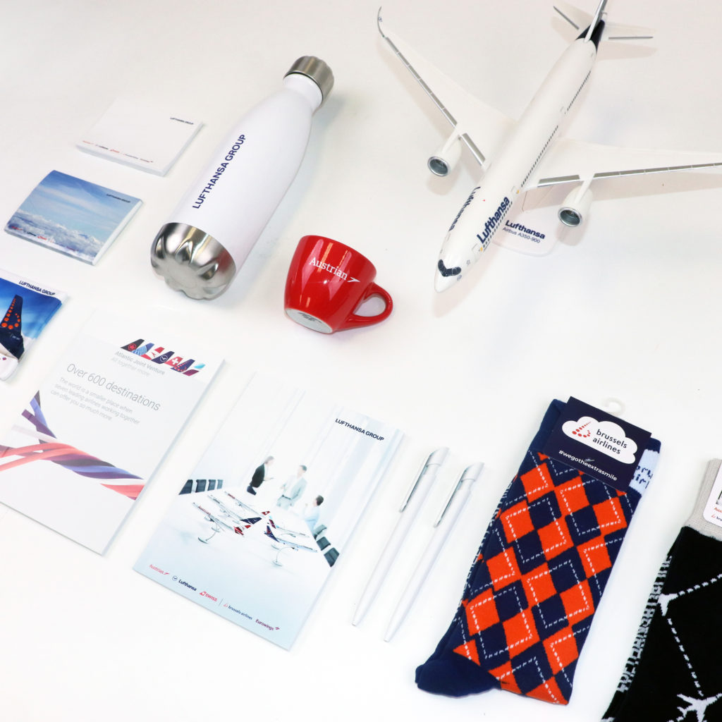 Airplane promotional items including: sticky notes, tumblers, coffee mugs, socks, and other printing materials
